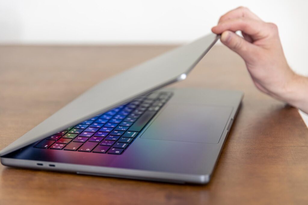 mans hand opens laptop with multicolored glowing screen 169016 33671 mans hand opens laptop with multicolored glowing screen 169016 33671